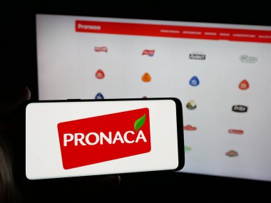 Stuttgart, Almanya - 04-09-2025: Ekvador 'lu gıda şirketi Pronaca' nın logosunu elinde tutan kişi web sitesinin önünde ekranda. Telefon ekranına odaklan.