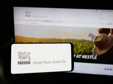 Stuttgart, Almanya - 04-09-2025: Üzerinde İsviçre yiyecek ve içecek şirketi Nestle S.A. logosu olan akıllı telefonu web sitesinin önünde tutan kişi. Telefon ekranına odaklan.