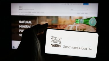 Stuttgart, Almanya - 04-09-2025: Üzerinde İsviçre yiyecek ve içecek şirketi Nestle S.A. logosu bulunan cep telefonu sahibi kişi web sitesinin önünde ekranda. Telefon ekranına odaklan.