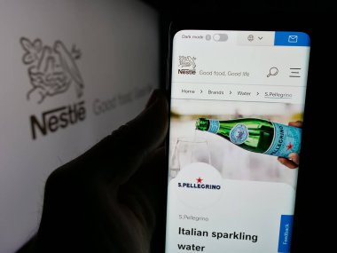 Stuttgart, Almanya - 04-09-2025: İsviçre yiyecek ve içecek şirketi Nestle S.A. 'nın web sitesi olan akıllı telefonu logo önünde ekrana yansıtan kişi. Telefon ekranının merkezine odaklan.