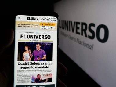 Stuttgart, Almanya - 04-09-2025: Ekvador gazetesi El Universo 'nun web sayfası logonun önünde cep telefonu tutan kişi. Telefon ekranının merkezine odaklan.