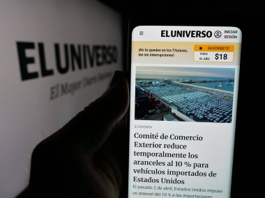 Stuttgart, Almanya - 04-09-2025: Ekvador gazetesi El Universo 'nun web sitesiyle logonun önünde akıllı telefon tutan kişi. Telefon ekranının merkezine odaklan.