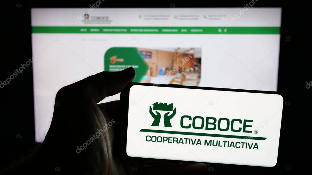 Stuttgart, Germany - 04-09-2025: Person holding mobile phone with logo of Cooperativa Boliviana de Cemento (COBOCE) on screen in front of web page. Focus on phone display.