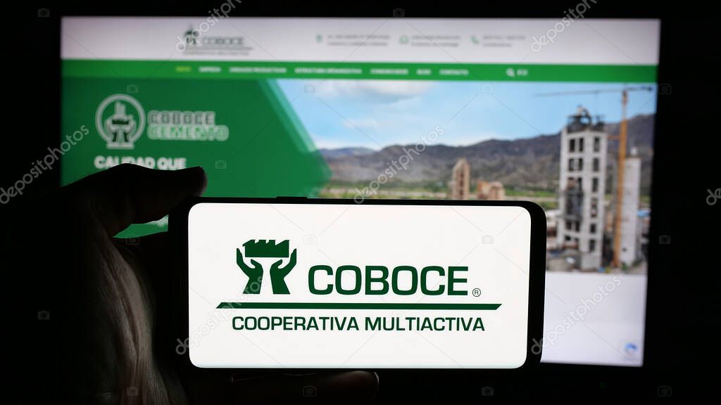 Stuttgart, Germany - 04-09-2025: Person holding cellphone with logo of Cooperativa Boliviana de Cemento (COBOCE) on screen in front of webpage. Focus on phone display.