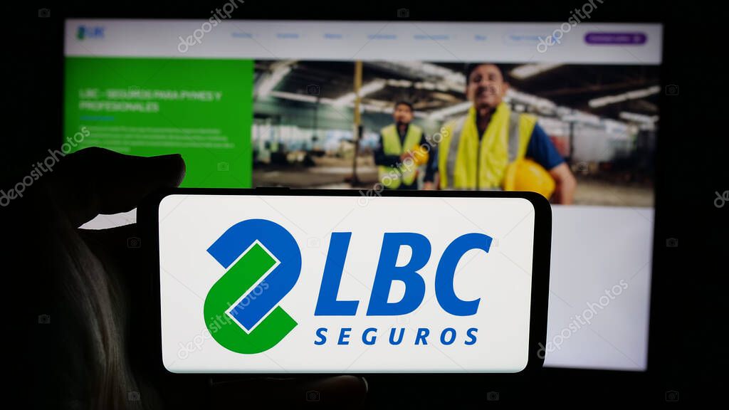 Stuttgart, Germany - 04-09-2025: Person holding cellphone with logo of Bolivian insurance company LBC Seguros on screen in front of webpage. Focus on phone display.