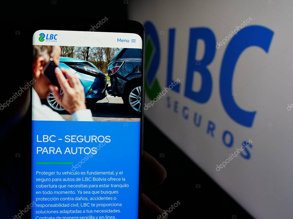 Stuttgart, Germany - 04-09-2025: Person holding smartphone with website of Bolivian insurance company LBC Seguros on screen in front of logo. Focus on center of phone display.