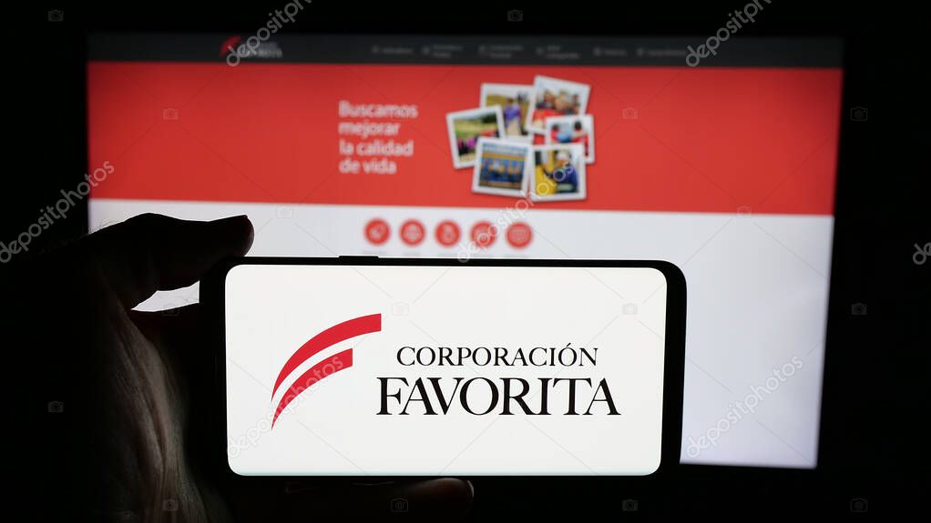 Stuttgart, Germany - 04-09-2025: Person holding cellphone with logo of retail company Corporacion Favorita C.A. on screen in front of webpage. Focus on phone display.