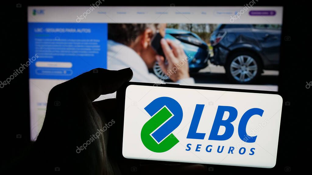 Stuttgart, Germany - 04-09-2025: Person holding mobile phone with logo of Bolivian insurance company LBC Seguros on screen in front of web page. Focus on phone display.