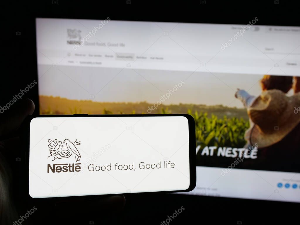 Stuttgart, Germany - 04-09-2025: Person holding smartphone with logo of Swiss food and beverage company Nestle S.A. on screen in front of website. Focus on phone display.
