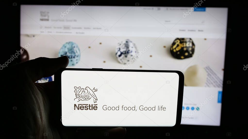 Stuttgart, Germany - 04-09-2025: Person holding cellphone with logo of Swiss food and beverage company Nestle S.A. on screen in front of webpage. Focus on phone display.