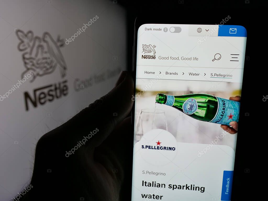Stuttgart, Germany - 04-09-2025: Person holding smartphone with website of Swiss food and beverage company Nestle S.A. on screen in front of logo. Focus on center of phone display.