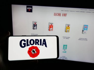 Stuttgart, Almanya - 04-09-2025: Perulu mandıra şirketi Gloria S.A. 'nın logosunu elinde tutan kişi web sitesinin önünde ekranda. Telefon ekranına odaklan.