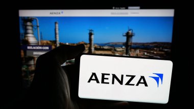 Stuttgart, Almanya - 04-09-2025: Perulu emlak şirketi Aenza S.A.A. 'nın logosuna sahip cep telefonu sahibi kişi Web sayfasının önünde ekranda. Telefon ekranına odaklan.