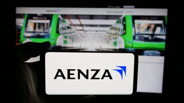 Stuttgart, Almanya - 04-09-2025: Perulu emlak şirketi Aenza S.A.A. 'nın logosuyla cep telefonu tutan kişi Web sayfasının önünde ekranda. Telefon ekranına odaklan.