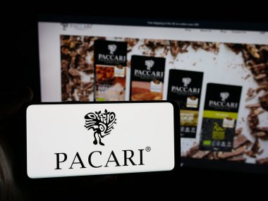 Stuttgart, Almanya - 04-09-2025: Ekvador 'lu şirket Pacari Chocolate' nın logosuna sahip akıllı telefon sahibi kişi web sitesinin önünde ekranda. Telefon ekranına odaklan.
