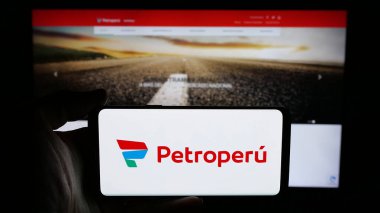 Stuttgart, Almanya - 04-09-2025: Web sayfası önünde Petroleos del Peru S.A. (Petroperu) şirketinin logosunun bulunduğu cep telefonu sahibi kişi. Telefon ekranına odaklan.