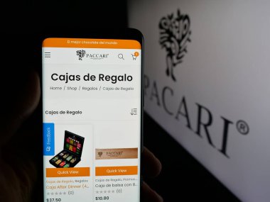Stuttgart, Almanya - 04-09-2025: Ekvatorlu şirket Pacari Chocolate 'nın web sitesi ile logonun önünde akıllı telefon tutan kişi. Telefon ekranının merkezine odaklan.