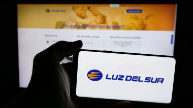 Stuttgart, Almanya - 04-17-2025: Perulu enerji şirketi Luz del Sur S.A.A. logosu olan cep telefonu sahibi kişi Web sayfasının önünde ekranda. Telefon ekranına odaklan.
