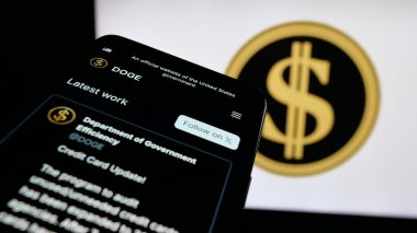 Stuttgart, Almanya - 04-17-2025: ABD Devlet Verimliliği Bakanlığı (DOGE) web sayfası logonun önünde ekranda. Telefon ekranının sol üst kısmına odaklan.