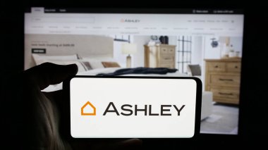 Stuttgart, Almanya - 04-17-2025: ABD 'li Ashley Mobilya Endüstri Şirketi' nin logosunun bulunduğu cep telefonu web sayfası önünde ekranda. Telefon ekranına odaklan.