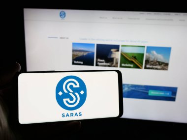 Stuttgart, Almanya - 04-17-2025: İtalyan petrol şirketi Saras S.P.A. 'nın logosunu elinde tutan kişi web sitesinin önünde ekranda. Telefon ekranına odaklan.