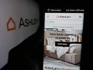 Stuttgart, Almanya - 04-17-2025: ABD 'li Ashley Mobilya Endüstrisi' nin web sitesi ile akıllı telefon sahibi kişi logonun önünde ekranda. Telefon ekranının merkezine odaklan.