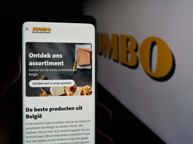 Stuttgart, Almanya - 04-17-2025: Hollandalı şirket Koninklijke Jumbo Food Groep 'in web sitesi ile logo önünde akıllı telefon taşıyan kişi. Telefon ekranının merkezine odaklan.