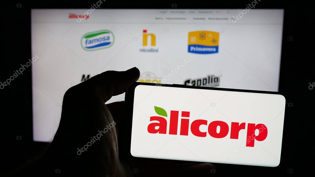 Stuttgart, Germany - 04-09-2025: Person holding mobile phone with logo of consumer goods company Alicorp S.A.A. (Peru) on screen in front of web page. Focus on phone display.