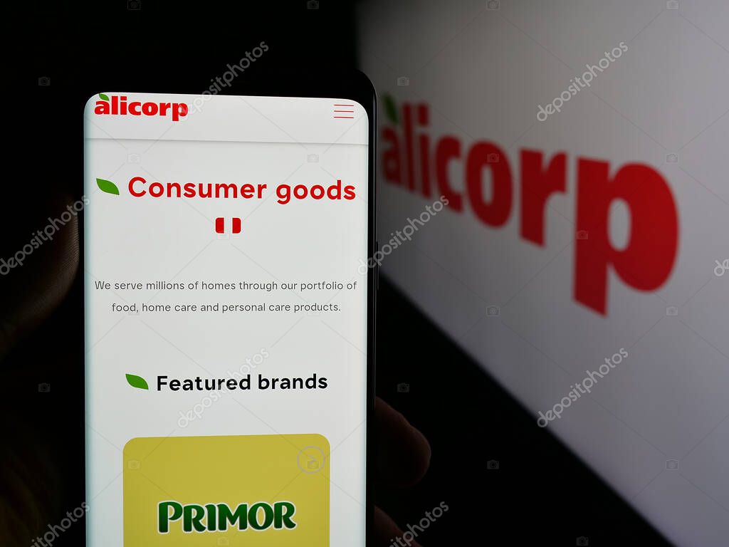 Stuttgart, Germany - 04-09-2025: Person holding smartphone with website of consumer goods company Alicorp S.A.A. (Peru) on screen in front of logo. Focus on center of phone display.