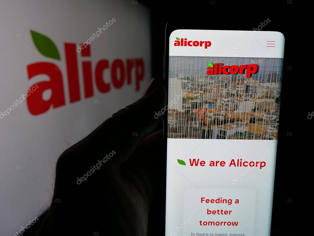 Stuttgart, Germany - 04-09-2025: Person holding cellphone with web page of consumer goods company Alicorp S.A.A. (Peru) on screen in front of logo. Focus on center of phone display.