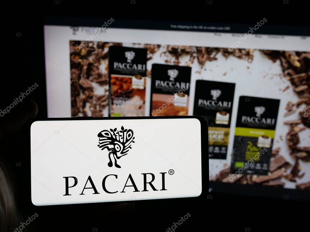 Stuttgart, Germany - 04-09-2025: Person holding smartphone with logo of Ecuadorian company Pacari Chocolate on screen in front of website. Focus on phone display.