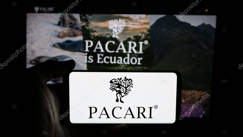 Stuttgart, Germany - 04-09-2025: Person holding cellphone with logo of Ecuadorian company Pacari Chocolate on screen in front of webpage. Focus on phone display.