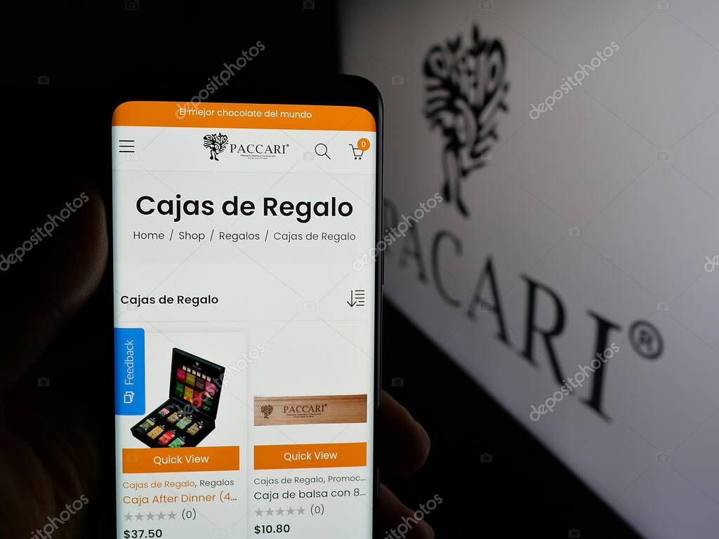 Stuttgart, Germany - 04-09-2025: Person holding smartphone with website of Ecuadorian company Pacari Chocolate on screen in front of logo. Focus on center of phone display.