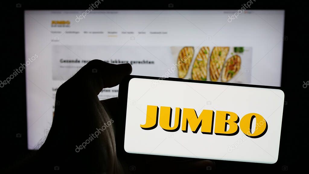 Stuttgart, Germany - 04-17-2025: Person holding mobile phone with logo of Dutch company Koninklijke Jumbo Food Groep on screen in front of web page. Focus on phone display.