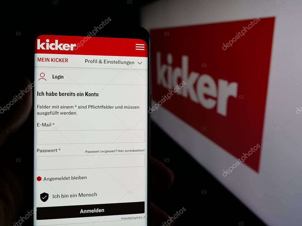 Stuttgart, Germany - 04-17-2025: Person holding smartphone with website of German football and sports magazine Kicker on screen in front of logo. Focus on center of phone display.