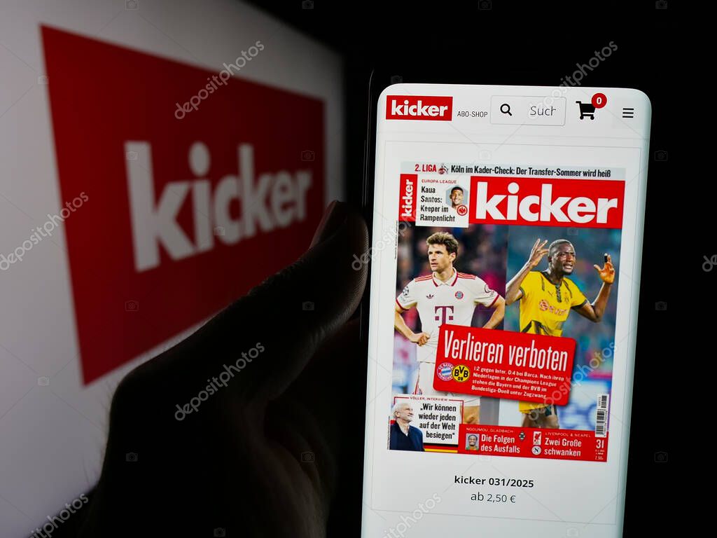 Stuttgart, Germany - 04-17-2025: Person holding cellphone with web page of German football and sports magazine Kicker on screen in front of logo. Focus on center of phone display.