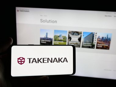 Stuttgart, Almanya - 04-24-2025: İnşaat şirketi Takenaka Corporation 'ın logosunun bulunduğu akıllı telefonu web sitesinin önünde tutan kişi. Telefon ekranına odaklan.