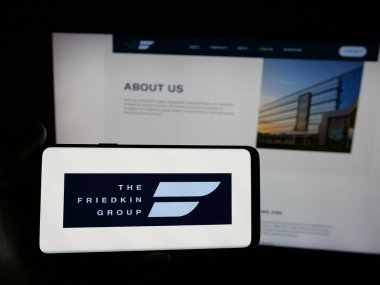Stuttgart, Almanya - 04-24-2025: ABD 'li şirket The Friedkin Group' un logosunu taşıyan kişi web sitesinin önünde ekranda. Telefon ekranına odaklan.