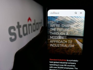 Stuttgart, Almanya - 04-24-2025: ABD 'li Standard Industries Inc. şirketinin web sitesi ile akıllı telefon sahibi kişi logonun önünde ekranda. Telefon ekranının merkezine odaklan.