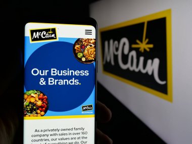 Stuttgart, Almanya - 04-24-2025: Kanadalı gıda şirketi McCain Foods Limited 'in web sayfası ile cep telefonu tutan kişi logonun önünde ekranda. Telefon ekranının merkezine odaklan.