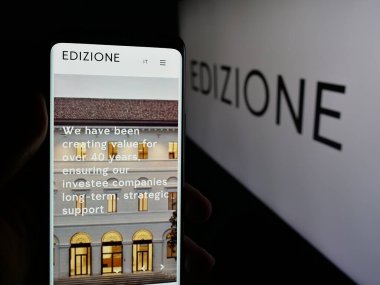 Stuttgart, Almanya - 04-24-2025: İtalyan yatırım şirketi Edizione S.P.A. 'nın web sitesi ile akıllı telefonu olan kişi logonun önünde ekranda. Telefon ekranının merkezine odaklan.