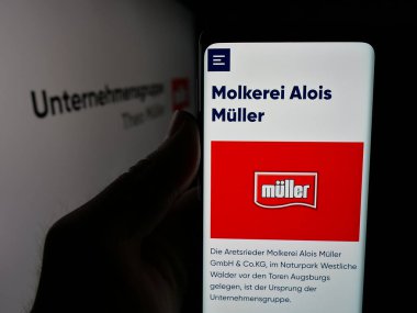 Stuttgart, Almanya - 04-24-2025: Süt ürünleri şirketi Unternehmensgruppe Theo Mueller 'in web sitesi ile akıllı telefon taşıyan kişi logonun önünde ekranda. Telefon ekranının merkezine odaklan.