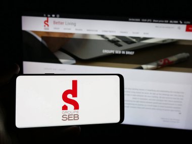 Stuttgart, Almanya - 04-25-2025: Fransız cihaz şirketi SEB S.A. 'nın logosunu elinde tutan kişi web sitesinin önünde ekranda. Telefon ekranına odaklan.