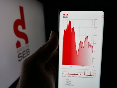 Stuttgart, Almanya - 04-25-2025: Fransız cihaz şirketi SEB S.A. 'nın web sitesi ile akıllı telefonu olan kişi logonun önünde ekranda. Telefon ekranının merkezine odaklan.