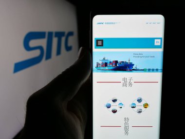 Stuttgart, Almanya - 04-25-2025: SITC International Holding Co. Ltd. şirketinin web sitesi ile akıllı telefon sahibi kişi logonun önünde ekranda. Telefon ekranının merkezine odaklan.