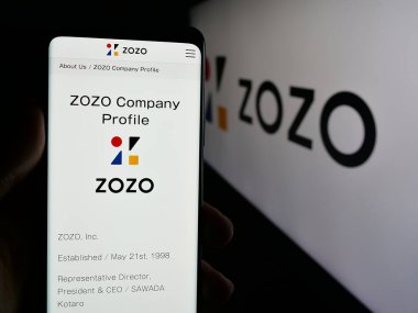 Stuttgart, Almanya - 04-25-2025: Japon e-ticaret şirketi ZOZO Inc. 'nin web sitesi ile akıllı telefon sahibi kişi logonun önünde ekranda. Telefon ekranının merkezine odaklan.