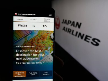 Stuttgart, Almanya - 04-25-2025: Havayolu şirketi Japan Airlines Co. Ltd. (JAL) 'in web sitesi ile akıllı telefon sahibi kişi logonun önünde ekranda. Telefon ekranının merkezine odaklan.