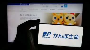 Stuttgart, Almanya - 04-25-2025: Japon Posta Sigorta Şirketi Ltd. 'sinin logosu olan cep telefonu web sayfasının önünde ekranda. Telefon ekranına odaklan.