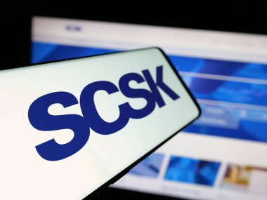 Stuttgart, Almanya - 04-25-2025: Japon bilişim şirketi SCSK Corporation 'ın logosuna sahip akıllı telefon web sitesinin önünde ekranda. Telefon ekranının merkez soluna odaklan.