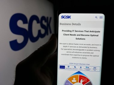 Stuttgart, Almanya - 04-25-2025: Japon bilişim şirketi SCSK Corporation 'ın web sitesi ile akıllı telefon sahibi kişi logonun önünde ekranda. Telefon ekranının merkezine odaklan.